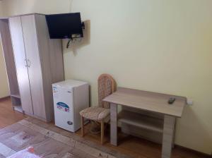 Habitación con mesa y nevera pequeña. en Жемчужина Иссык - Куля en Cholpon-Ata