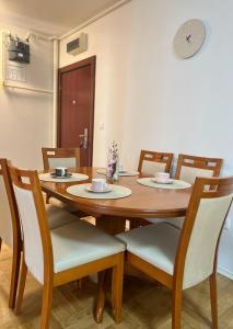 a dining room table with chairs and a clock on the wall at Arena Cosy apartment in Zagreb +4 photos