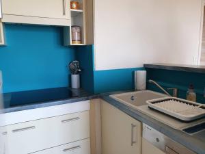 kuchnia ze zlewem i niebieską ścianą w obiekcie Bel appartement rénové au centre-ville de PERROS-GUIREC - Réf 920 w mieście Perros-Guirec