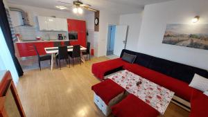 uma sala de estar com um sofá vermelho e uma cozinha em Apartment Disa em Kaštela