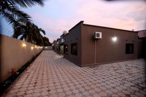 a brick road with a building and a palm tree at Cloud One Apartments in Kitwe