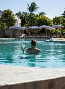 a woman in a swimming pool with a frisbee at Hotel Pipa Atlântico in Pipa