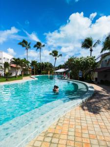 a person swimming in a swimming pool with palm trees at Hotel Pipa Atlântico in Pipa