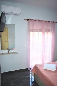 a bedroom with a pink curtain and a mirror at Venice Apartments in Limenaria