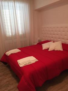 sypialnia z czerwonym łóżkiem i ręcznikami w obiekcie Itaka w mieście LʼAquila