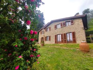 a large brick house with pink roses in front of it at Villa Camelia Tuscany in Pescia