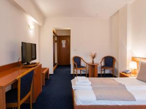 a hotel room with a bed and a flat screen tv at Hotel Excelsior in Timişoara