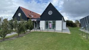a black and white house with a large yard at Recreatie Chalet Oostkapelle VZ652 in Oostkapelle +6 photos