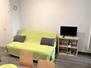 Cette petite chambre comprend un lit vert et une télévision. dans l'établissement Appartement bien équipé à 500m plage et commerces à PERROS-GUIREC - Réf 948, à Perros-Guirec