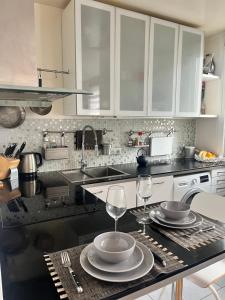 a kitchen with white cabinets and two wine glasses on a counter at Appartement cosy près de la Seine in Boulogne-Billancourt +6 photos