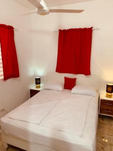 Schlafzimmer mit einem weißen Bett und roten Vorhängen in der Unterkunft Caribbean Domicile in Las Terrenas
