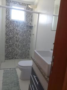 a bathroom with a toilet and a sink and a shower at Praia in Praia Grande +3 photos