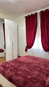 - une chambre avec un grand lit et des rideaux rouges dans l'établissement Les Chambres, à Pagani
