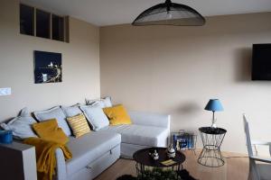 a living room with a white couch with yellow pillows at Appartement entièrement rénové avec SUPERBE VUE sur la Baie Sainte-Anne à TREGASTEL - Ref 96 in Trégastel