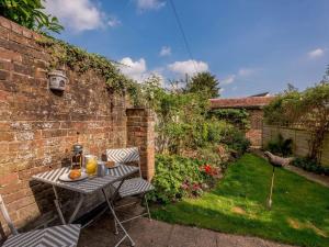 a table and chairs in a garden with a brick wall at 1 bed in Sedlescombe 83845 in Sedlescombe