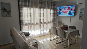 un soggiorno con tavolo, sedie e TV di Casa Alisios a Telde