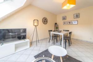 een woonkamer met een tafel en stoelen en een televisie bij Le central in Mulhouse