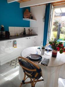 une cuisine avec une table blanche et un mur bleu dans l'établissement La Suite 27 bis, duplex indépendant, à Guingamp