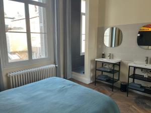 een slaapkamer met een bed, een wastafel en een spiegel bij Une escapade au cœur de Tours in Tours
