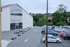 a parking lot with cars parked in front of a building at Aux portes du marché in Bar-le-Duc