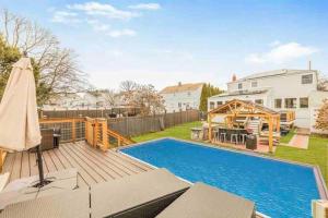 a backyard with a swimming pool and a wooden deck at Entire home- pool, gym, theater. 10 min from NYC. in Yonkers