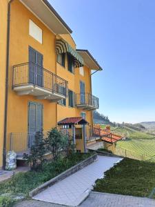 ein gelbes Gebäude mit Balkon an der Seite in der Unterkunft Soggiorno con splendida vista in Monforte dʼAlba