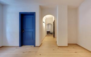 an empty hallway with a blue door and an arch way at Hotel Sachsenklemme in Fortezza