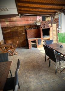 eine Außenterrasse mit Tischen, Stühlen und einem Grill in der Unterkunft Casa Adriana in Băile Herculane