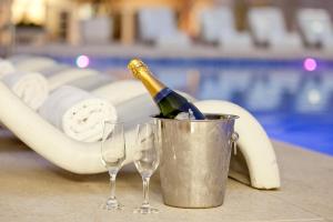 Ritz Plaza Hotel في جويز دي فورا: زجاجة من الشمبانيا في دلو بجوار كأسين من النبيذ