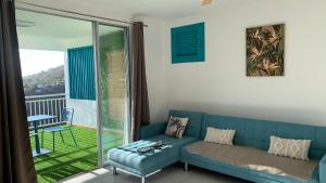 un soggiorno con un divano blu e un balcone di Appartement Ciel et Mer a Schœlcher