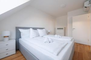 ein weißes Bett mit zwei Handtüchern darüber in der Unterkunft SYMPHONY Apartments 40 - Modern Loft with Terrace and Grill in Central Location in Wien