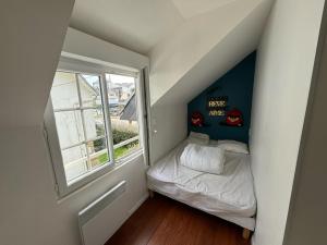 a small attic room with a bed and a window at Belle villa 150 m Carnac plage in Carnac