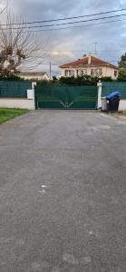a green gate in a driveway in front of a house at Studio plein Sud au calme in Montauban