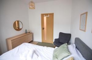 ein Schlafzimmer mit einem Bett, einem Stuhl und einem Spiegel in der Unterkunft Apartament Sikorskiego in Posen