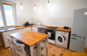 a kitchen with a refrigerator and a table with a washing machine at Apartament Sikorskiego in Poznań