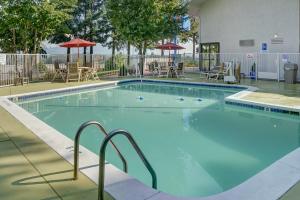 ein großer Pool mit Stühlen und Sonnenschirmen in der Unterkunft Motel 6-Eugene, OR - South Springfield in Eugene