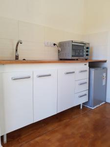 a kitchen with white cabinets and a microwave on a counter at Atila de montaña in San Martín de los Andes