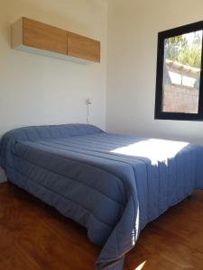 a blue bed in a white room with a window at Atila de montaña in San Martín de los Andes
