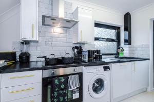 Una cocina blanca con lavadora y secadora. en New 2 Bed House - Perfect for Contractors & Families By AV Stays Short Lets St Helens en Saint Helens