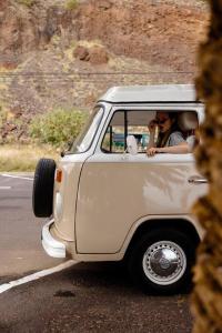 une personne dans une petite voiture blanche en descendant la route dans l'établissement Tommy, a '77 VW Bay stylish Van, à Los Cristianos