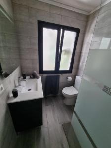uma casa de banho com um lavatório, um WC e uma janela. em CASA KARLOS em Arrecife