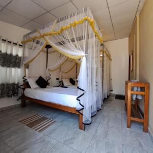 a bedroom with a bed with a canopy at Etnico Surf Resort in Arugam Bay