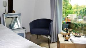 1 dormitorio con silla azul, mesa y ventana en Ferienhaus in Bovenkarspel mit Garten, Terrasse und Grill, en Bovenkarspel