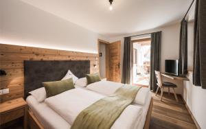 Un dormitorio con una cama grande y una ventana en Enzianhof - Nature Apartments, en San Giovanni in Val Aurina