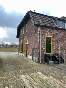 a red brick building with yellow doors and a porch at 't ouw ateljeeke in Budel