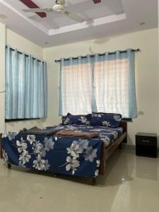 um quarto com uma cama com lençóis azuis e cortinas azuis em AnubhavGruha Holiday Home Nagpur em Nagpur