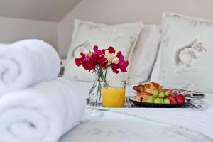 uma bandeja de pequeno-almoço com um prato de frutas e flores numa cama em Woodland Cottage em Llanasa