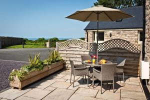 a table and chairs with an umbrella on a patio at Woodland Cottage in Llanasa