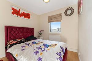 a bedroom with a bed with a red headboard and a window at Tranquility in Cheam