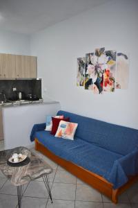 Sofá azul en la sala de estar con mesa en Venice Apartments, en Limenaria